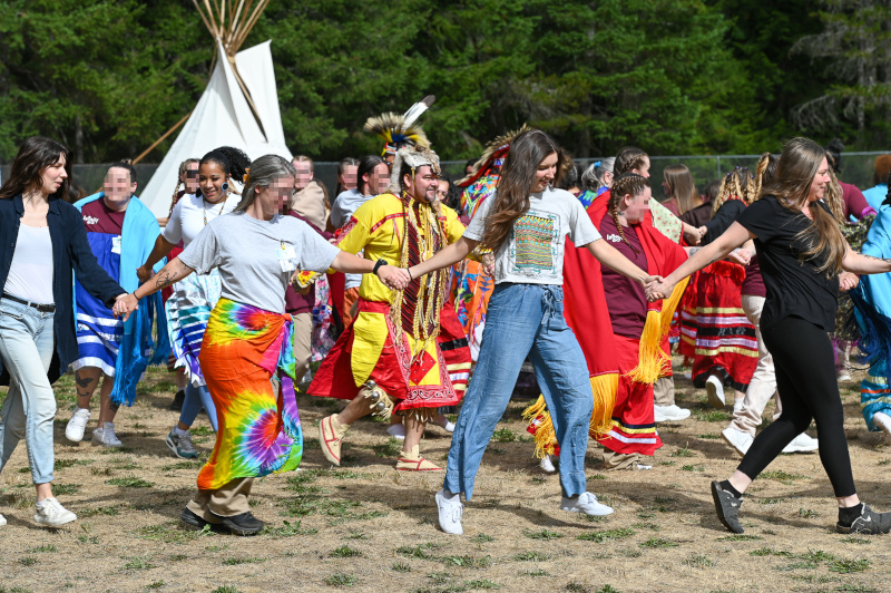 Participants of the powwow at MCCCW hold hands and dance.