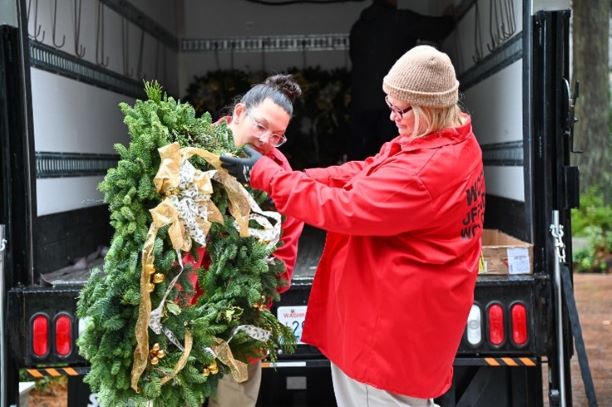 Jennifer Ramsey and Lani Kraabell offload wreaths from a truck.