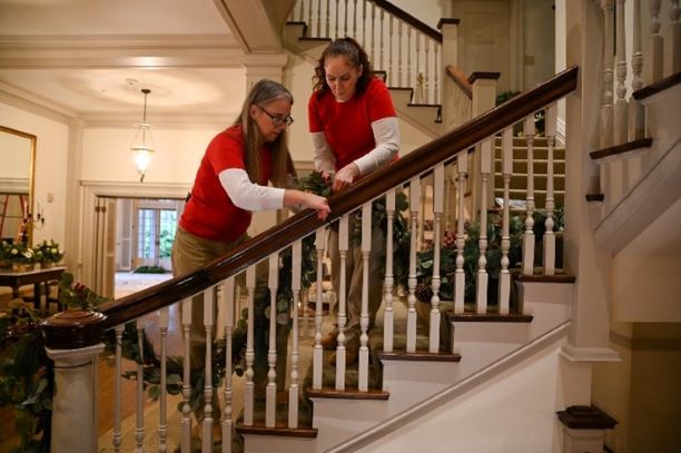 Alexia Devlin and Elizabeth Turner Murphy hang garland on a staircase.