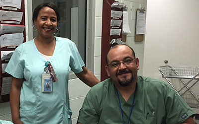 male and female nurses in scrubs smiling at the camera