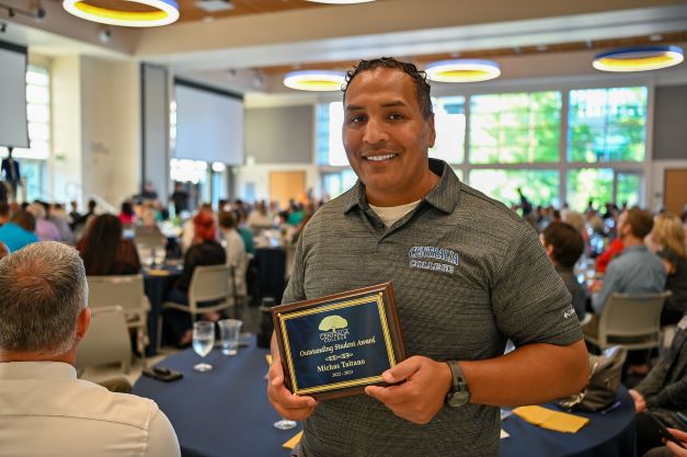 Man holds an award plaque.