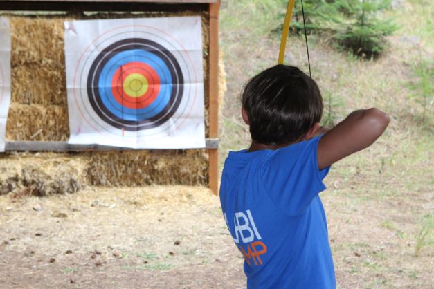 A camper gets ready to shoot an arrow at the archery range.