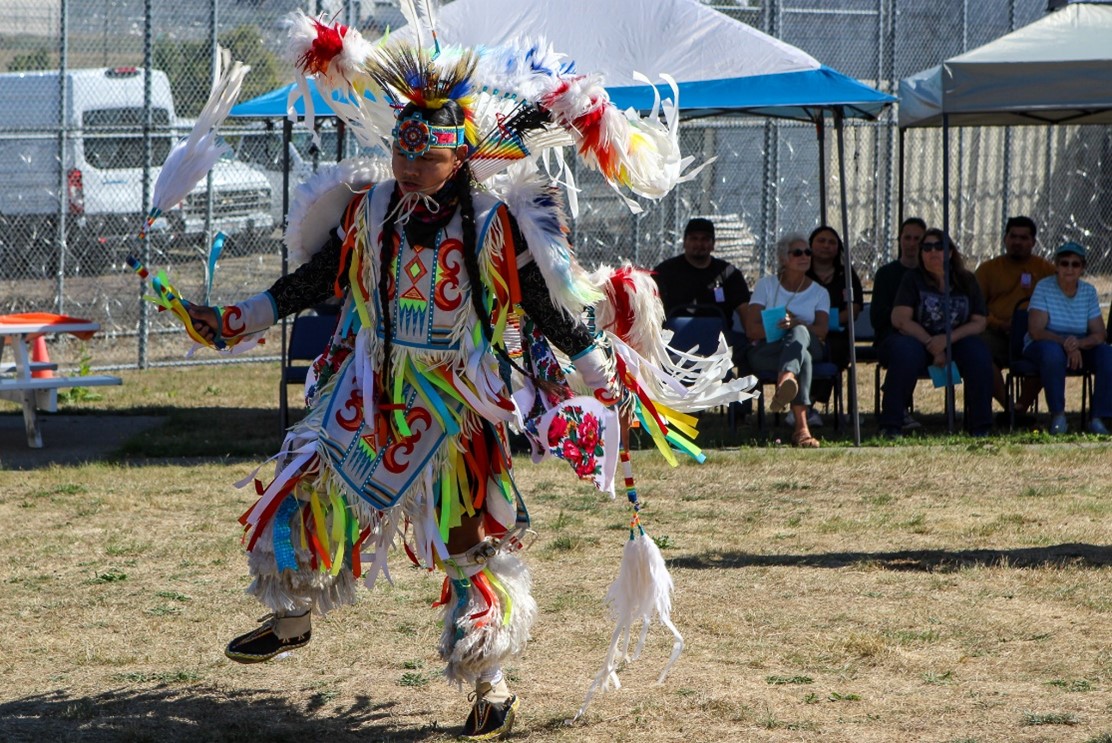 Man in traditional regalia dances in front of crowd