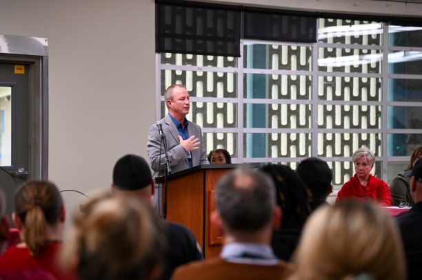 Man stands at podium, addressing a crowd.