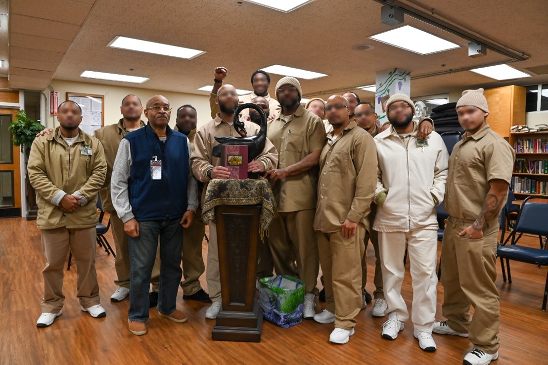 Group of indivduals standing behind a statue of a bird.