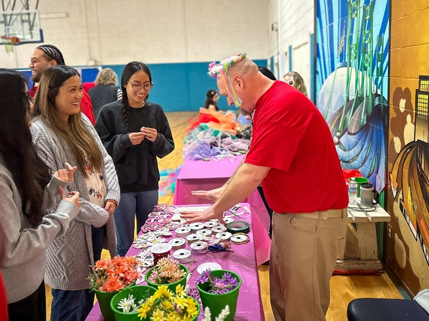 An incarcerated individual helps families with supplies for the tutu making station.