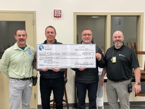 Four men standing holding a large check.