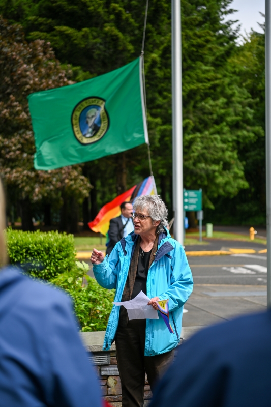 Woman talking to crowd with flags in the background